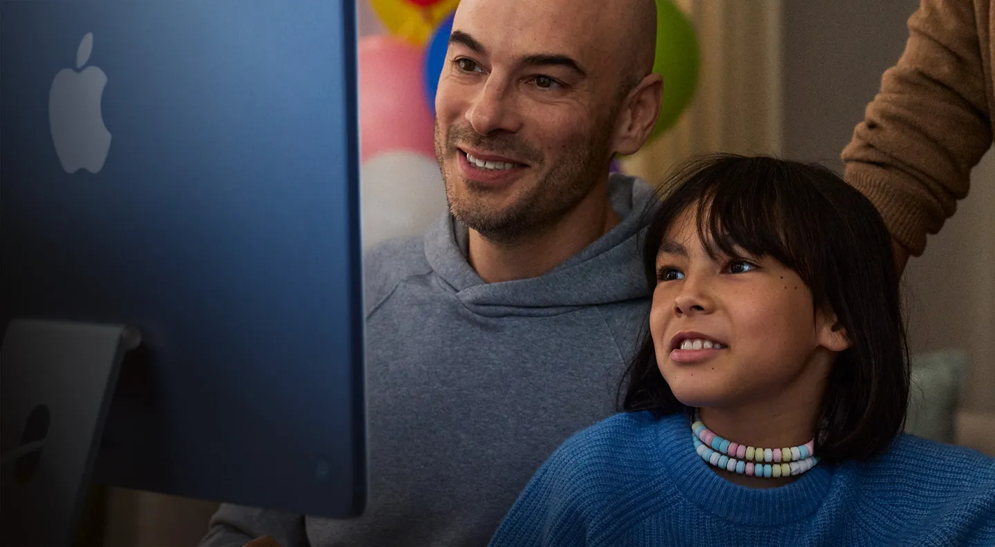 A child using an iMac at home with a parent nearby